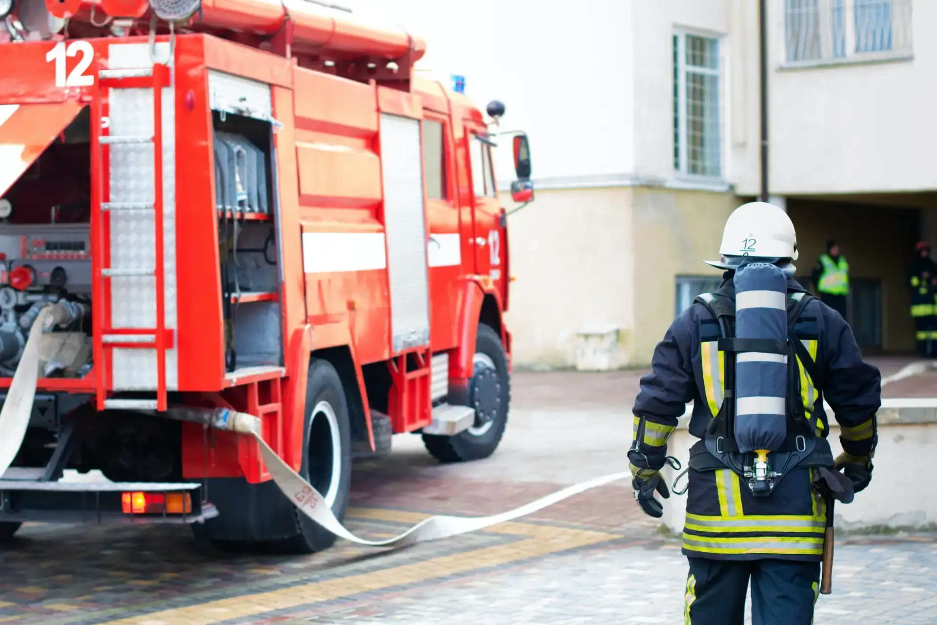 Bombeiro com equipamento de proteção respiratória ao lado de caminhão de combate a incêndio